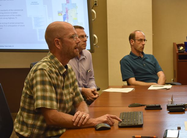 man speaks at table with other people
